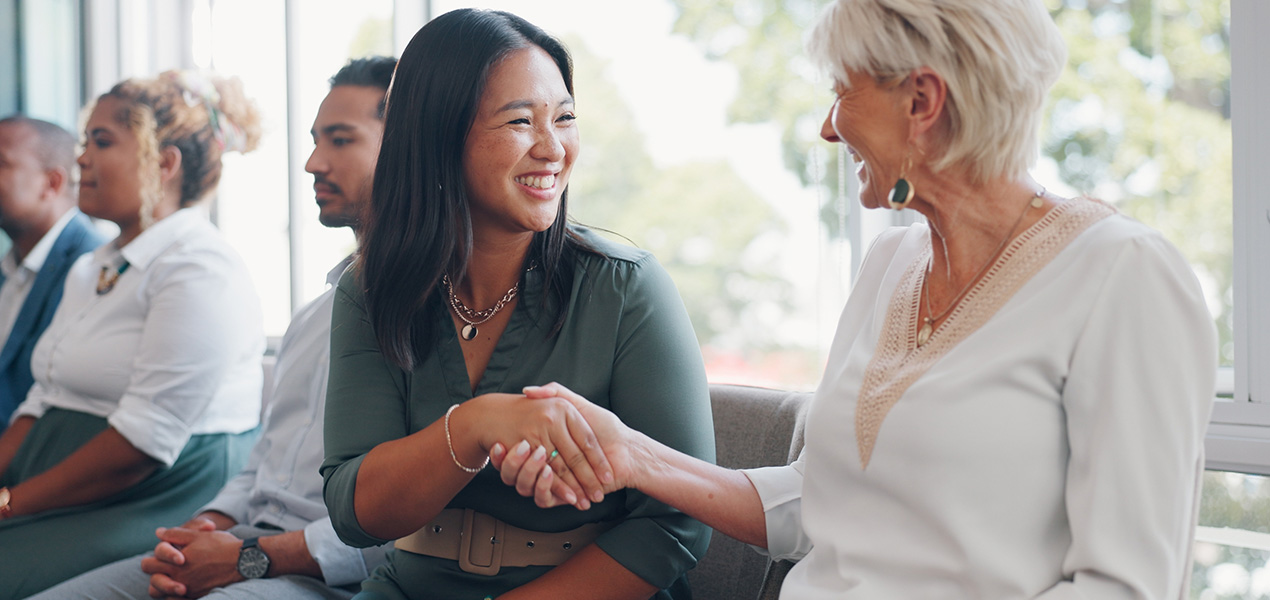 Two people at a conference shaking hands and introducing themselves.